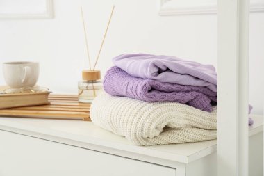 Işık duvarının yanındaki rafta örülmüş süveterler.