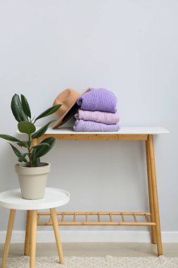 Işık duvarının yanındaki masada örülmüş süveter ve şapka yığını.