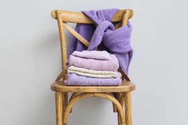 Hafif duvarın yanında örülmüş kazaklı ahşap sandalye.