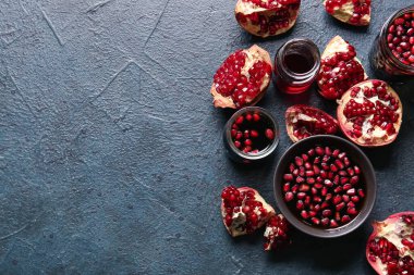 Kavanozlar ve bir kase nar pekmezi ve siyah arka planda taze meyveler.