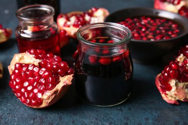 Kavanozlar dolusu nar pekmez ve siyah zemin üzerinde taze meyveler.