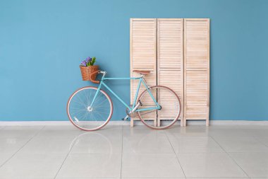 Modern bisiklet ve ahşap katlı ekran boş odada mavi duvarın yanında.