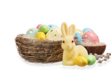 Beyaz arka planda boyanmış Paskalya yumurtaları ve tavşan yuvası