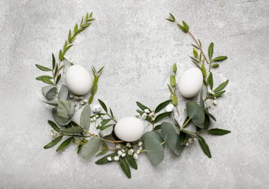 Paskalya yumurtalı şık çelenk, okaliptüs yaprakları ve açık arkaplanda çiçekler