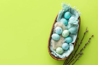 İçinde boyanmış Paskalya yumurtaları ve yeşil arka planda söğüt dalları olan sepet.