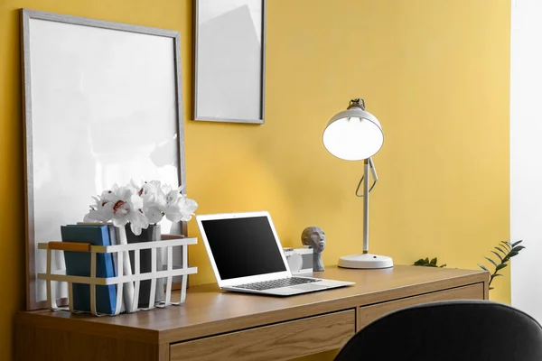 Nowoczesne Miejsce Pracy Laptopem Ramami Świecącą Lampą Przy Żółtej Ścianie — Zdjęcie stockowe