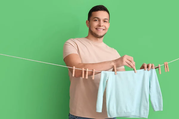 Young Man Hanging Children Sweatshirt Clothespins Green Background — Stock Photo, Image