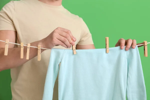 Jongeman Opknoping Kindersweatshirt Met Wasknijpers Groene Achtergrond Close — Stockfoto