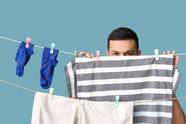 青い背景にきれいな洗濯や服をぶら下げ若い男 — ストック写真