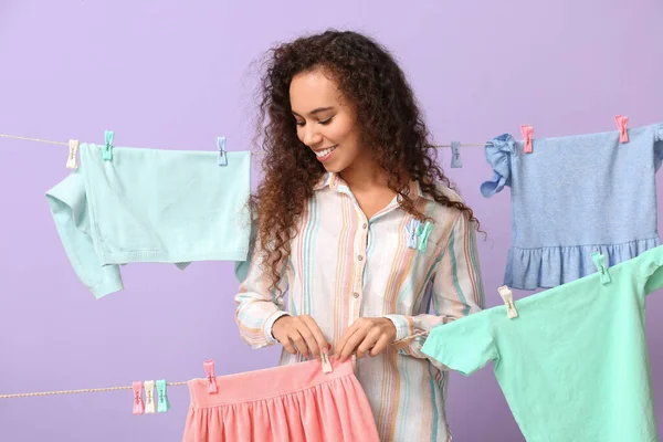 Young African American Woman Hanging Children Skirt Clothespin Lilac Background — Stock Photo, Image