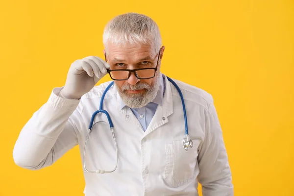 Sarı Arka Planda Gözlüklü Steteskoplu Olgun Bir Erkek Doktor — Stok fotoğraf