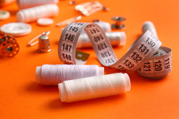 Катушки и измерительная лента на оранжевом фоне, крупный план