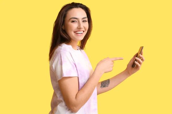 Glimlachende Vrouw Die Wijst Naar Een Mobiele Telefoon Een Gele — Stockfoto
