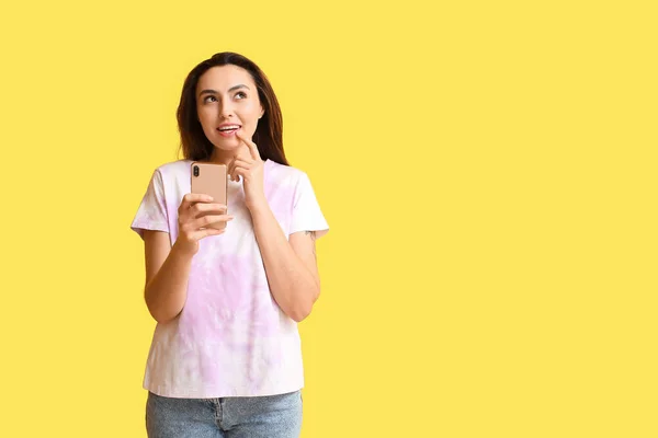 黄色の背景に携帯電話のチェックメールメッセージを持つ夢のような女性 — ストック写真