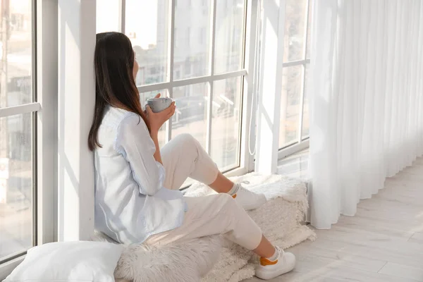 Pretty Young Asian Woman Drinking Tea While Sitting Window Sill — Stock Photo, Image