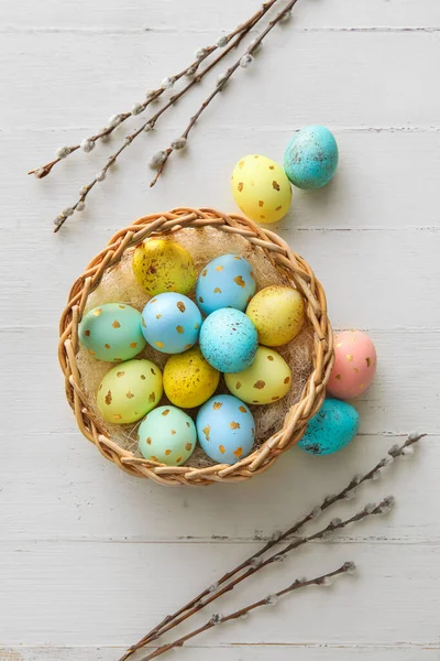 带彩绘复活节彩蛋和柳枝的篮子 背景为轻型木制 — 图库照片