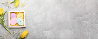 Lezzetli Paskalya kurabiyeleri ve grunge arkaplanındaki lale çiçekleriyle dolu bir kutu.