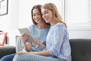 Evde tablet bilgisayar kullanan küçük kız kardeşler.