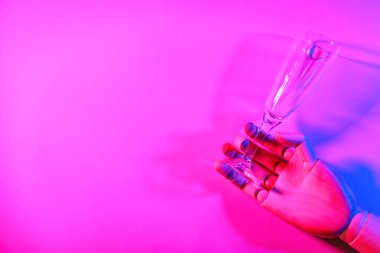 Koyu renk arka planda boş şampanya kadehi olan tahta manken eli.