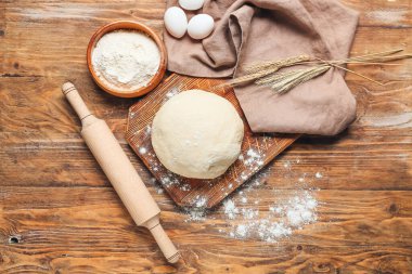 Çiğ hamur, un, merdane ve ahşap zemin üzerinde yumurta.