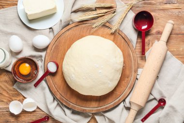 Ham hamurlu merdane ve ahşap arka planda malzemeler