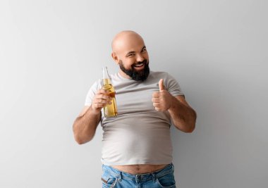 Bira içen kel adam arka planda baş parmağını kaldırıyor.