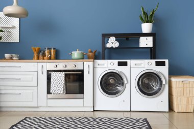 Modern çamaşır makinesi ve fırını olan şık bir mutfak.