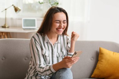 Odadaki koltukta cep telefonu mesajı okuyan duygusal bir kadın.