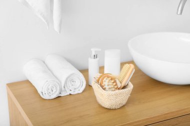 Masaj sepetleri, vücut fırçaları ve banyo malzemeleri lavabonun yanındaki masada.