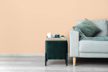 Şık bir kanepe ve bej duvarın yanında puf.