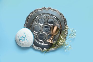 Hamursuz Bayramı yemeği tabağı, kippah ve fincanı mavi arka planda.