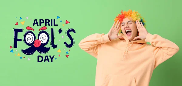緑の背景にカラフルなウィッグの面白い若い女性 4月愚か者の日のお祝い — ストック写真