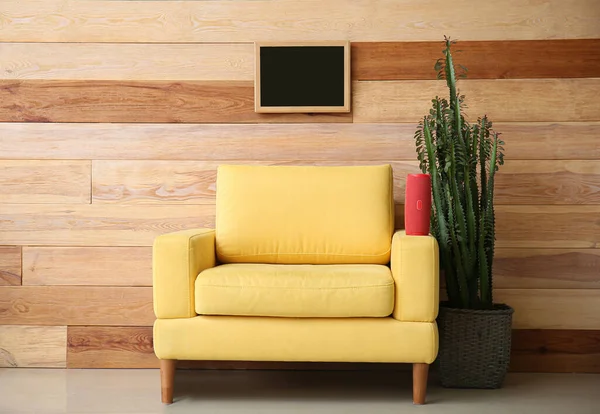 房间木制墙边扶手椅上的空白板和无线便携式扬声器 — 图库照片