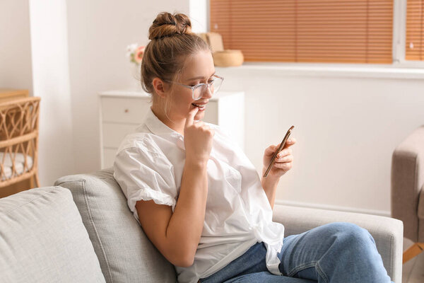 Pretty young woman using mobile phone at home