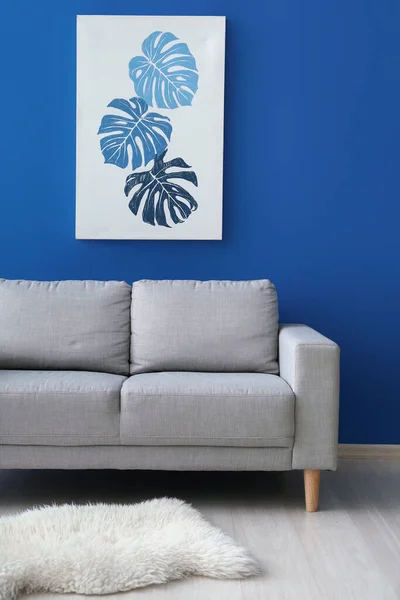 蓝墙旁边漂亮的图画和时髦的沙发 — 图库照片