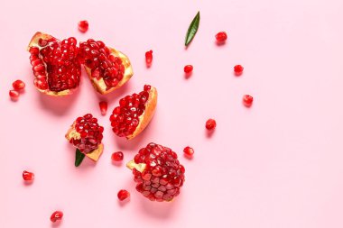 Pembe arka planda lezzetli olgun nar parçaları.