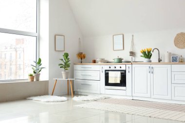 Mutfak tezgahları ve içi beyaz duvarın yanında güzel çiçekler.