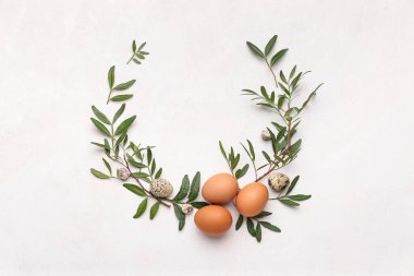 Hafif arka planda yapraklar ve yumurtalardan yapılmış zarif Paskalya çelengi