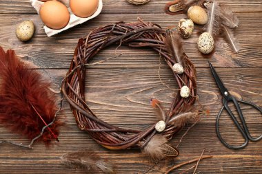 Ahşap zeminde Paskalya çelengi, yumurta, tüy ve makas kompozisyonu