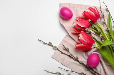 Pussy willow branches, painted Easter eggs and tulip flowers on light background