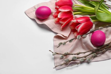 Pussy willow branches, painted Easter eggs and tulip flowers on light background, closeup