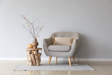 Masada renkli Paskalya yumurtaları ve ışık duvarının yanındaki koltuğu olan ağaç dalları.