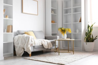 Mimoza çiçekli vazo ve oturma odasının içindeki masada bir kanepe.