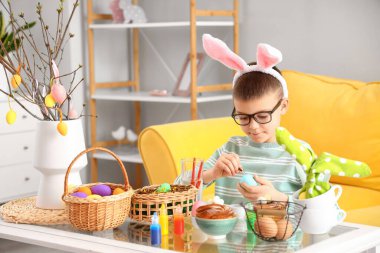 Evde paskalya yumurtası boyayan şirin bir çocuk.