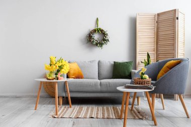 Paskalya kutlaması için dekore edilmiş oturma odasındaki ışık duvarının yanındaki koltuk ve koltuk.