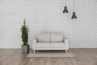 Gri tuğla duvarın yanında modern kanepe ve kaktüs