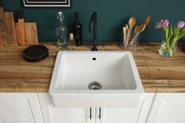 Lavabolu tezgahlar, vazodaki laleler ve renkli duvarların yanındaki mutfak aletleri.