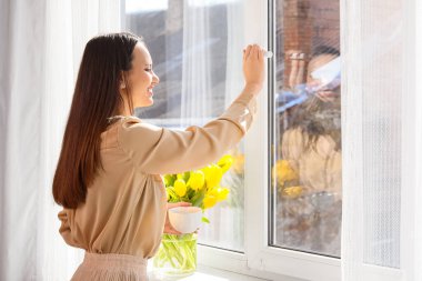 Güzel genç bayan pencerenin yanında sıcak kahve içiyor.