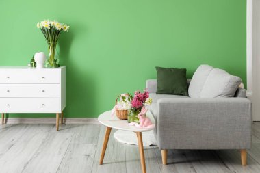 Çiçekli vazo ve oturma odasındaki kanepenin yanındaki paskalya tavşanı.