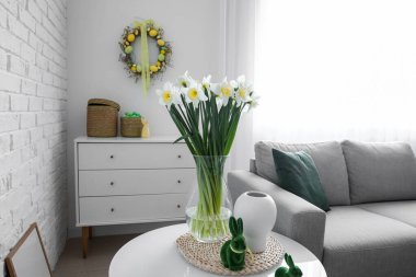 Paskalya tavşanı ve vazo nergis çiçekleri oturma odasındaki masada.